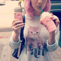 a woman with pink hair holding a drink and cell phone