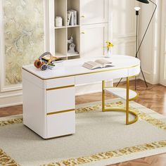 a white desk with gold trim on the top and bottom, in front of a large window