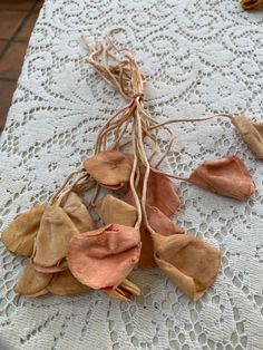 dried flowers are sitting on a white tablecloth with lace and twine around them