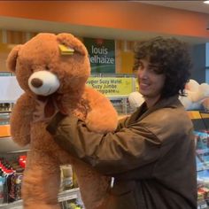 a man is holding a large teddy bear