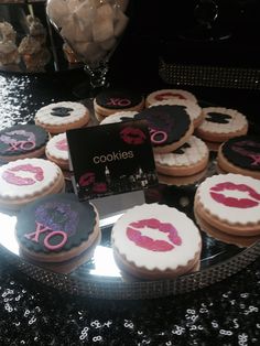 cookies decorated with pink and black icing are on a table in front of a mirror