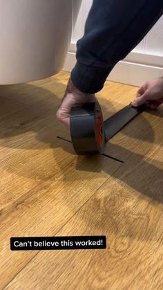 a person is using a tool to cut through the floor with a roll of tape