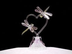 a glass figurine with two dragonflies on it's back and a bell in the shape of a heart