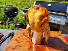 a chicken is sitting on top of a table next to a bbq and grill