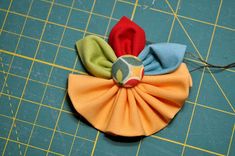 a close up of a cloth flower on a cutting board