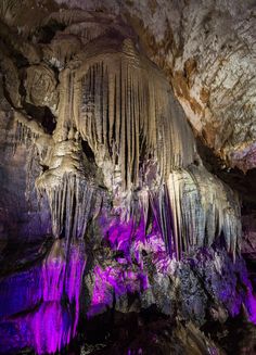 the inside of a cave with purple lights and stalate formations on the walls