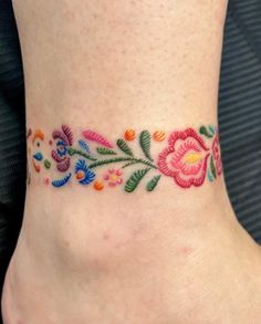 a woman's foot with colorful flowers and leaves on the bottom part of her ankle