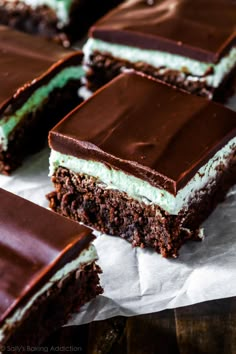 several pieces of cake sitting on top of a piece of parchment paper with chocolate frosting