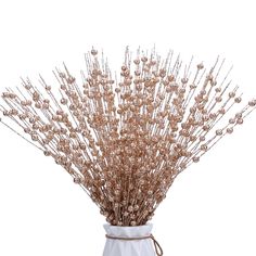 a white vase filled with lots of brown flowers