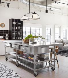 a kitchen island in the middle of a living room with lots of lights above it