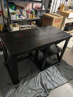 a black table sitting on top of a piece of plastic in a room filled with boxes and other items