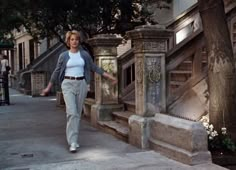 a woman walking down the sidewalk in front of some stairs