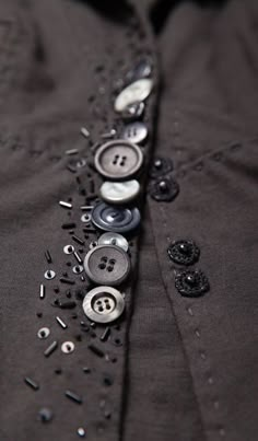 buttons and sequins are attached to the collar of a black shirt that is being worn by someone