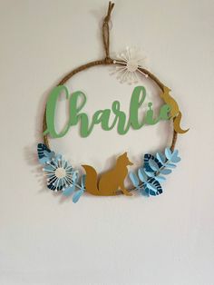 a wooden sign hanging on the wall that says charlie with blue flowers and a dog