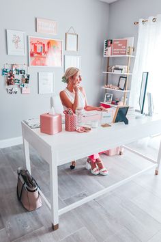 a woman sitting at a white desk in front of a laptop computer on top of a wooden table