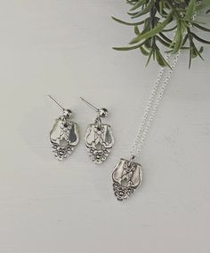 three pieces of jewelry sitting on top of a white surface next to a plant with green leaves