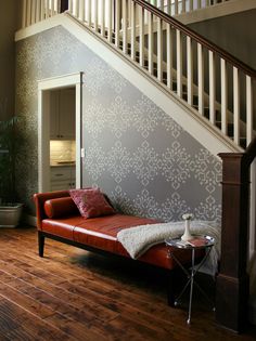 a red leather couch sitting under a stair case