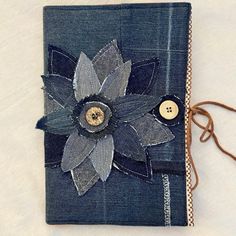 a blue book with a flower on the front and two buttons in the middle, sitting on a white surface