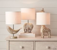 two lamps sitting on top of a dresser next to an elephant and giraffe figurine