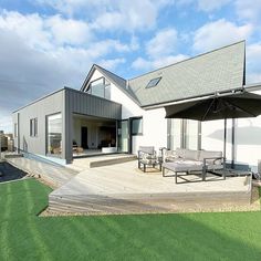 a house with an outdoor deck and patio furniture on the grass area next to it