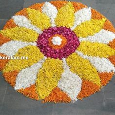 a colorful flower arrangement on the ground with white and yellow flowers in it's center