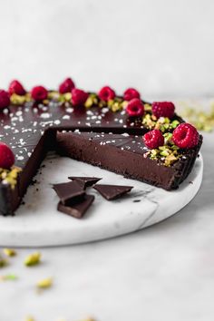 a chocolate cake with raspberries and pistachios on the top slice