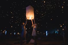 people releasing lanterns into the sky at night