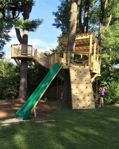 a child's play area with a slide and tree house in the back ground