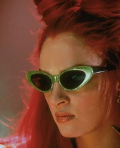 a woman with red hair wearing green sunglasses