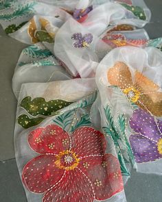 several pieces of cloth with flowers on them sitting on the floor next to each other