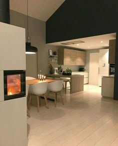 an open kitchen and dining room with a fireplace in the center is lit by two lights