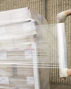 a person holding a large roll of plastic wrap