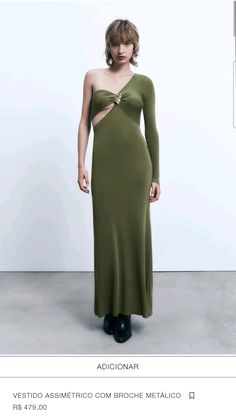 a woman in a long green dress standing next to a white wall