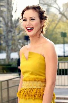 a woman in a yellow dress smiling at the camera