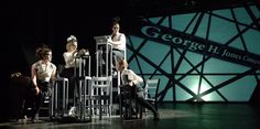 three people sitting on chairs in front of a stage