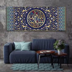 a living room with a couch, table and painting on the wall above it that has an arabic calligraphy written in gold