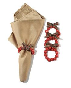 two napkins with red beads and bows on them next to a pair of shoes