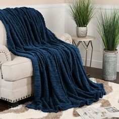 a couch with a blue blanket on top of it next to a potted plant