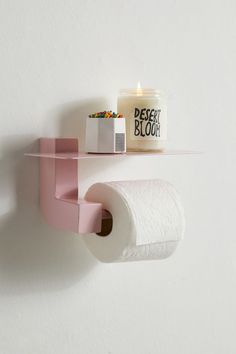 a bathroom shelf with two rolls of toilet paper on it and a candle next to it