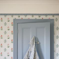 a blue door with floral wallpaper hanging on it's side by a towel rack