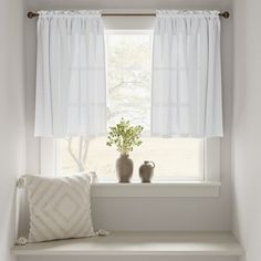 two vases sit on a window sill next to a pillow