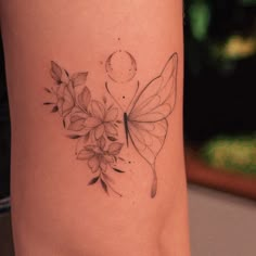 a woman's leg with flowers and a butterfly tattoo on the side of her thigh