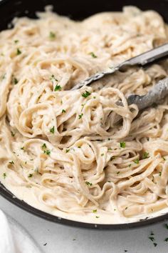 a pan filled with gluten - free alfredo sauce and garnished with parsley