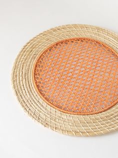 a round woven tray with an orange lining on the top and bottom, sitting on a white surface