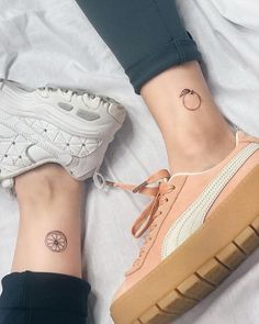 two people with matching tattoos on their feet, one has a small circle tattoo on the ankle