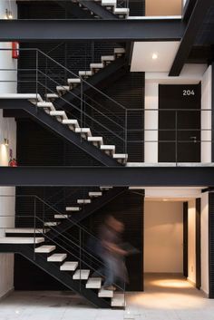 a man is walking down the stairs in a modern building with black walls and white balconies