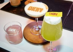 two drinks sitting on top of a table next to each other with the word dkny written on them