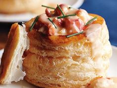 a pastry with meat and cheese on it is sitting on a white plate next to some bread