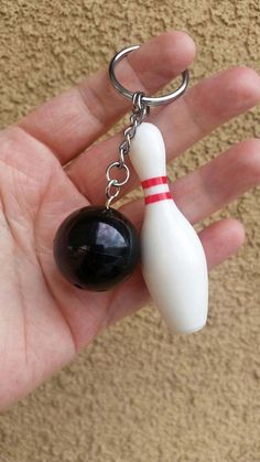 a hand holding a keychain with a bowling ball and skittle on it