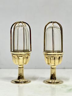 two golden candlesticks sitting on top of a white table next to each other